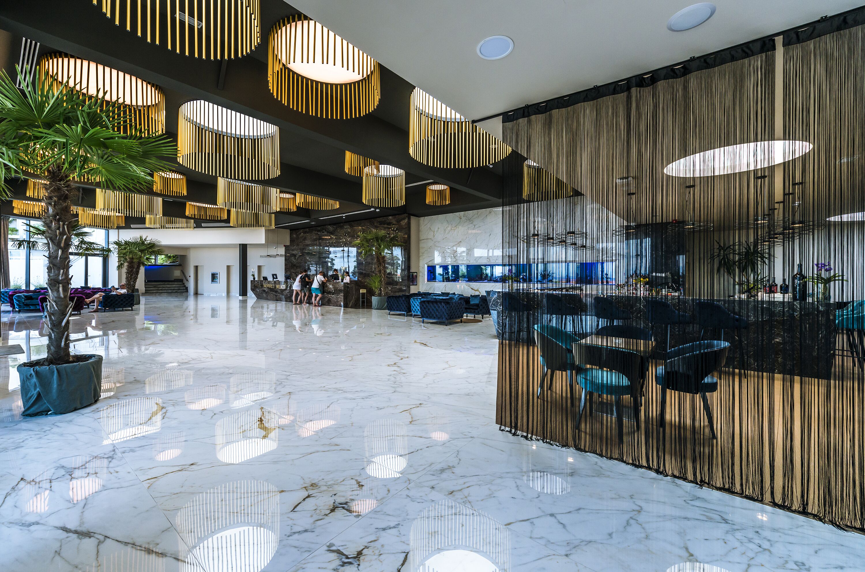 A spacious lobby with a marble floor, modern lighting fixtures, and seating areas.