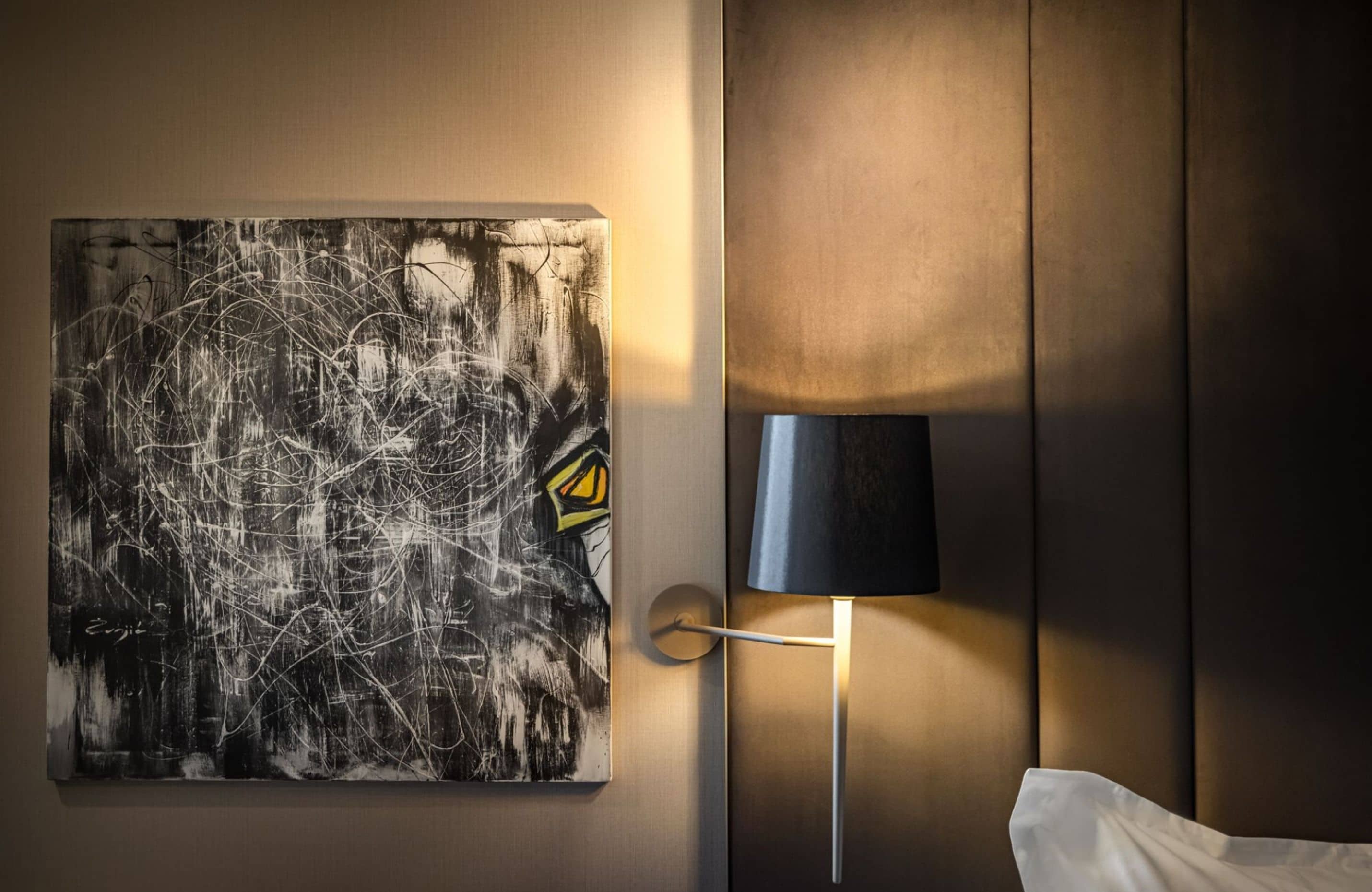 Ein Zimmer mit einem Bild an der Wand, einer Lampe und einem Bett.