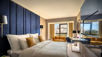 Une chambre d’hôtel moderne dotée d’un grand lit, d’un bureau, d’un canapé et offrant une vue sur la ville.