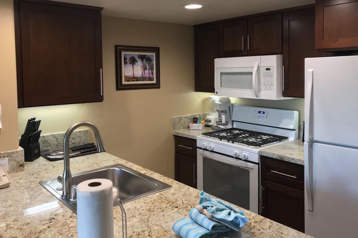 A kitchen with a stainless steel sink, a microwave, a stove, and a refrigerator.