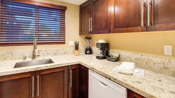 A kitchen with wooden cabinets, a granite countertop, a sink, a coffee maker, and a dishwasher.