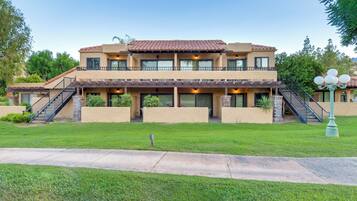 A two-story building with a flat roof, multiple windows, and a covered patio area.