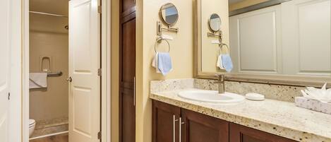 A bathroom with a double sink, wooden cabinets, a mirror, and a towel rack.