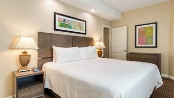 A hotel room with a large bed, two bedside tables, a nightstand, a wardrobe, and two wall-mounted lamps.