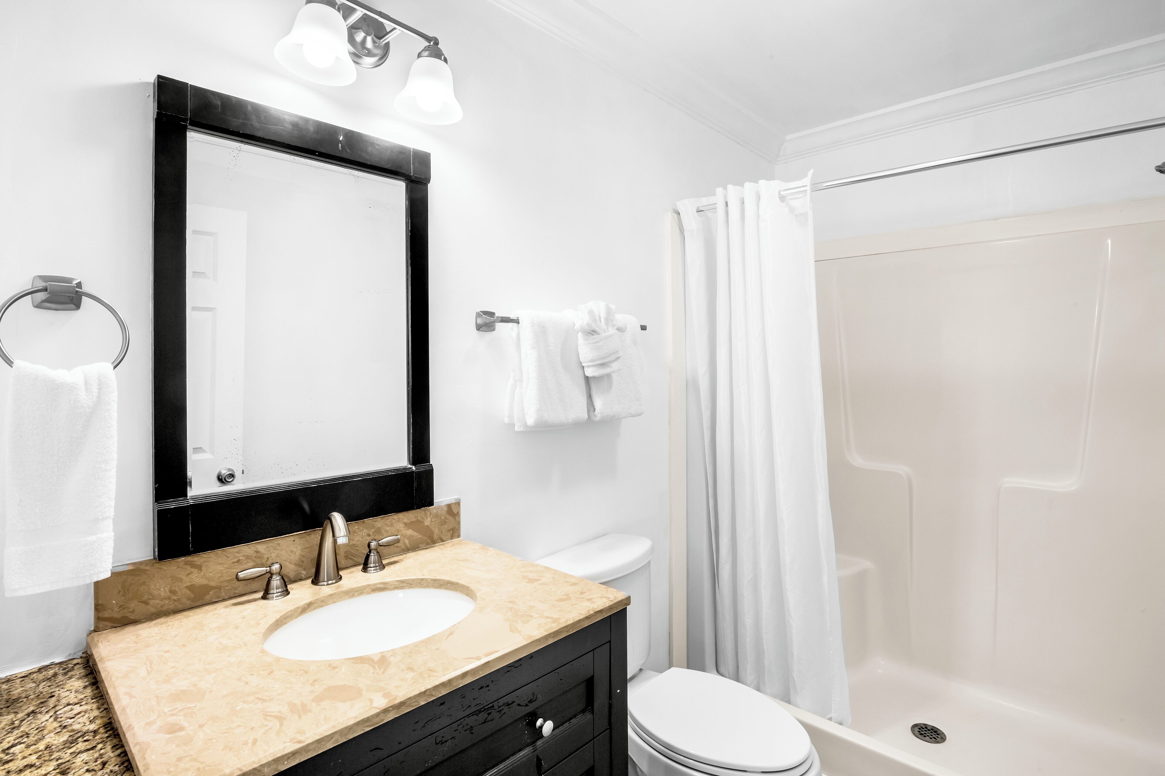 A bathroom with a sink, mirror, toilet, and shower.
