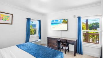 Un dormitorio con una cama, un escritorio y un ventanal con vista a la playa.