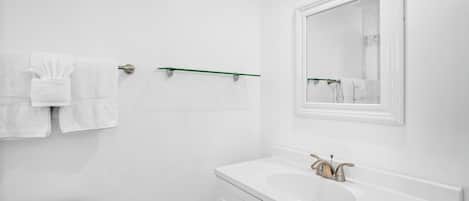 Ein modernes Badezimmer mit Waschbecken, Spiegel und Handtuchhalter.