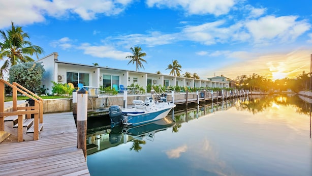 Un port de plaisance avec un quai, un bateau et une rangée de bâtiments dotés de grandes fenêtres.