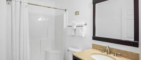 A bathroom with a bathtub, toilet, sink, and a large mirror.