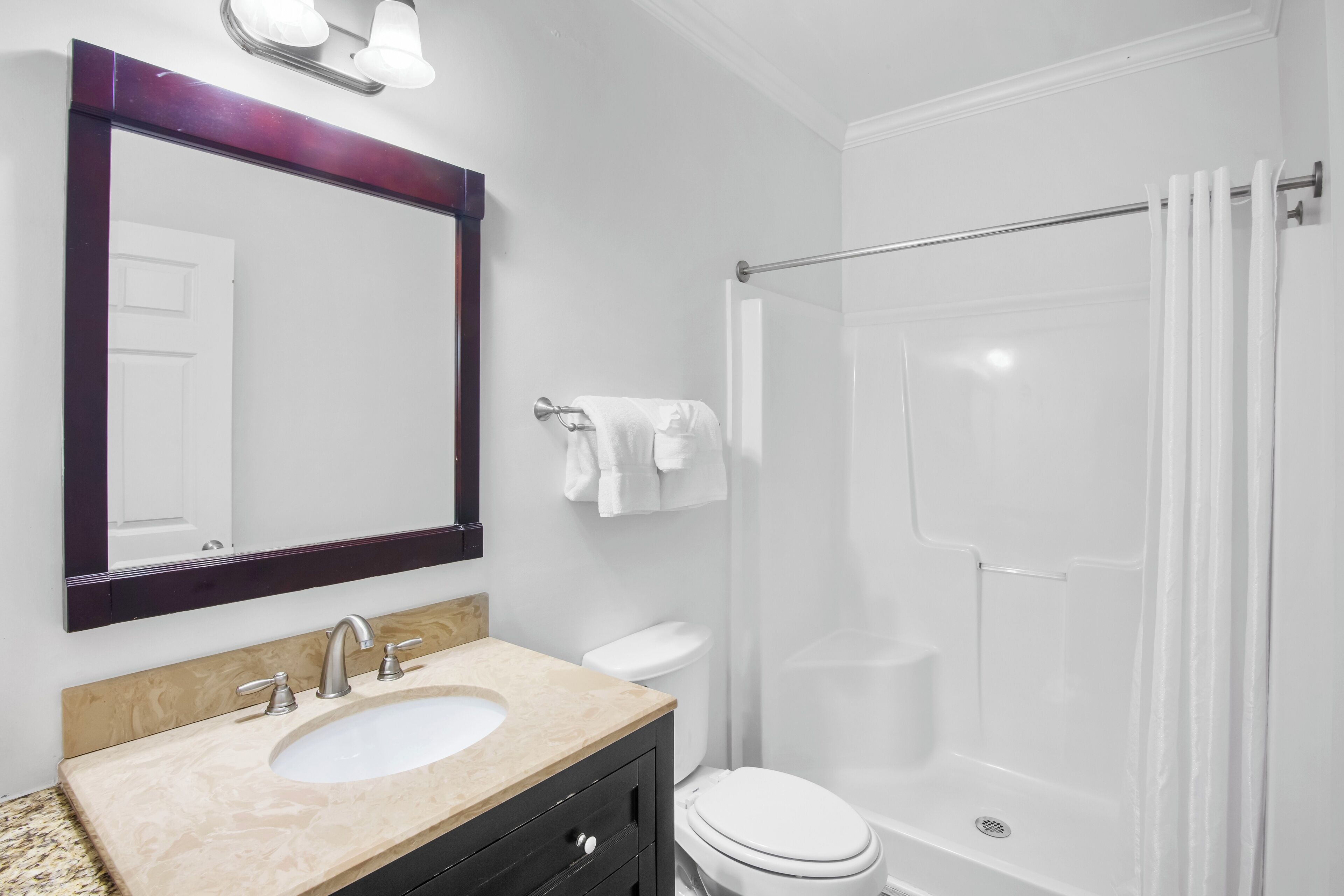 Een badkamer met een wastafel, spiegel, toilet en douche.
