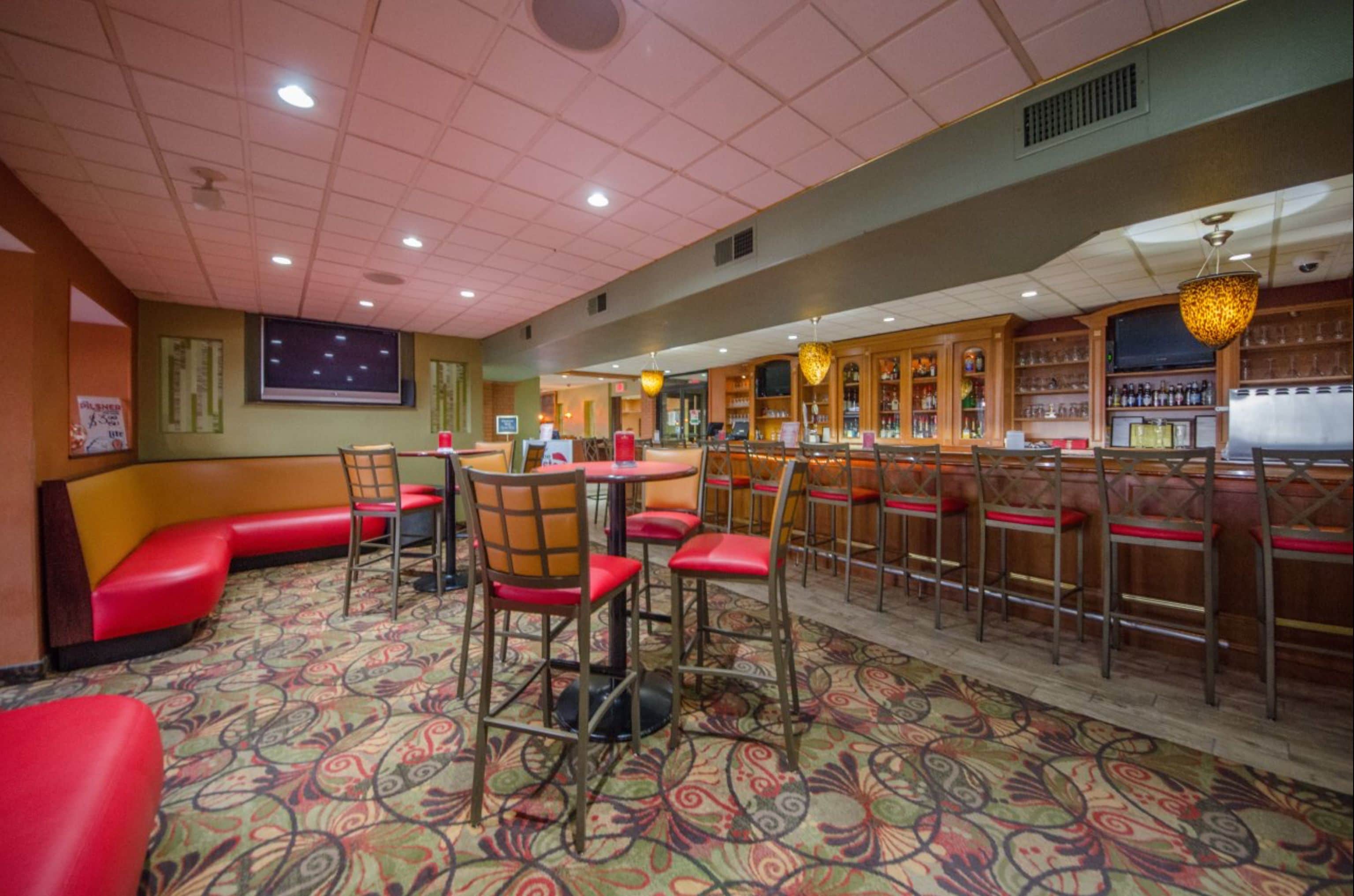 A restaurant with booths, high stools, and a bar area.