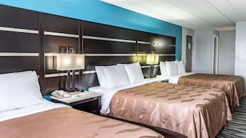 Habitación de hotel con dos camas, un cabecero grande, lámparas de noche y un teléfono en la mesita de noche.