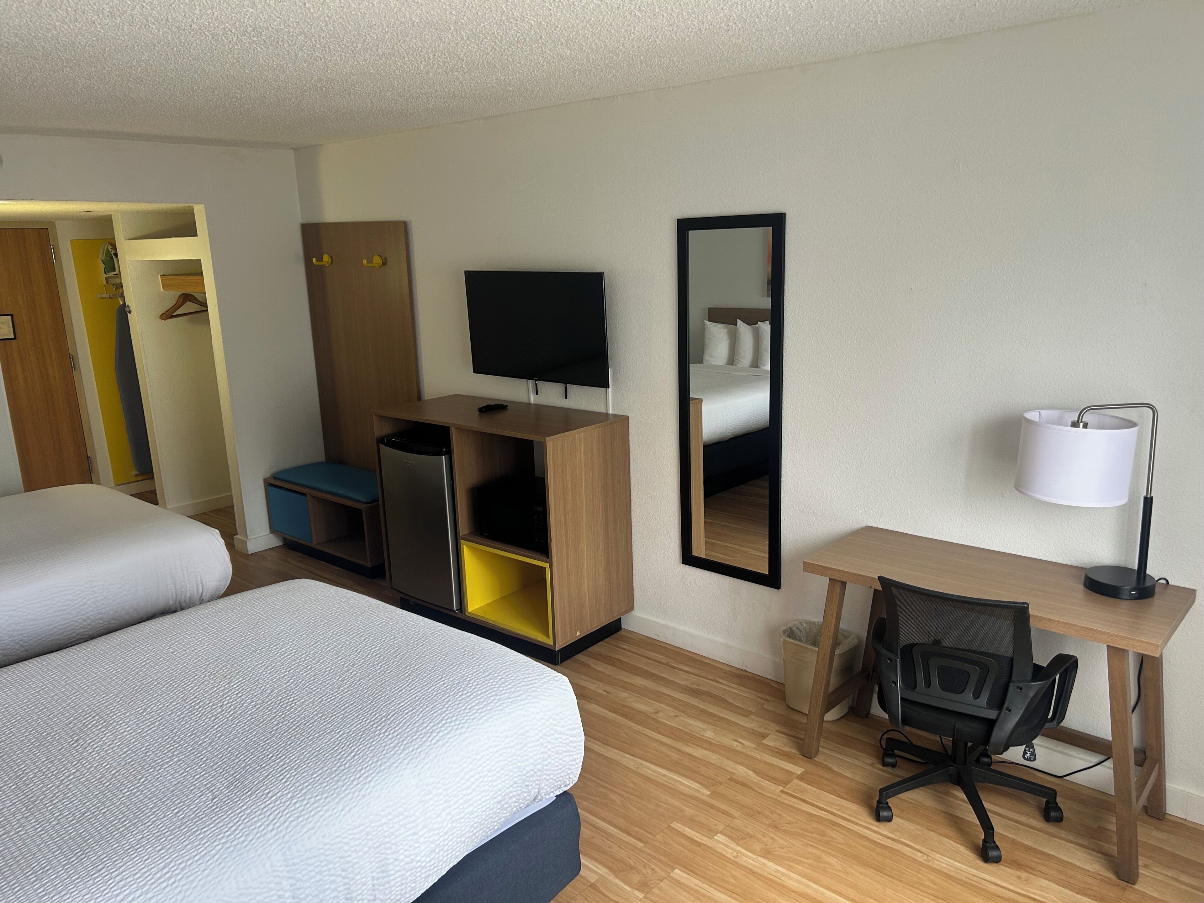Une chambre d’hôtel équipée d’un lit, d’un bureau, d’une chaise, d’une télévision, d’une armoire et d’un miroir.