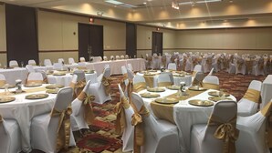 A banquet hall with round tables set for events, white chairs with gold sashes, and a carpeted floor. - Days Inn by Wyndham Sherman (Sherman)