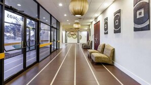 A hallway with glass doors, a sofa, and abstract wall art. - Days Inn by Wyndham Sherman (Sherman)