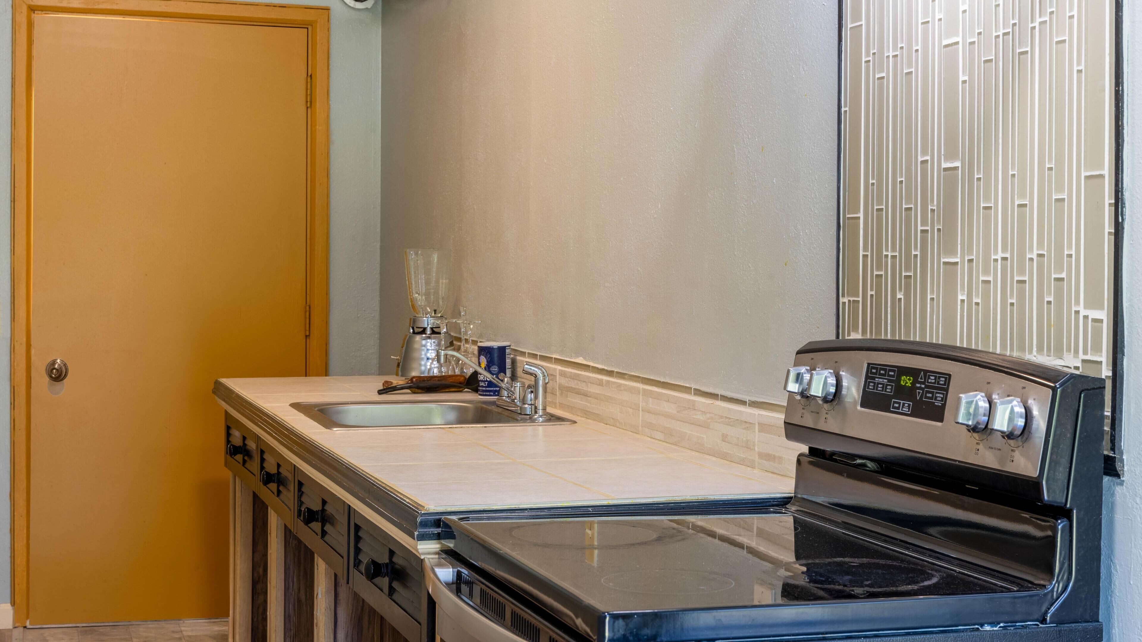Une cuisine équipée d’une cuisinière, d’un four, d’un évier et d’un mixeur.