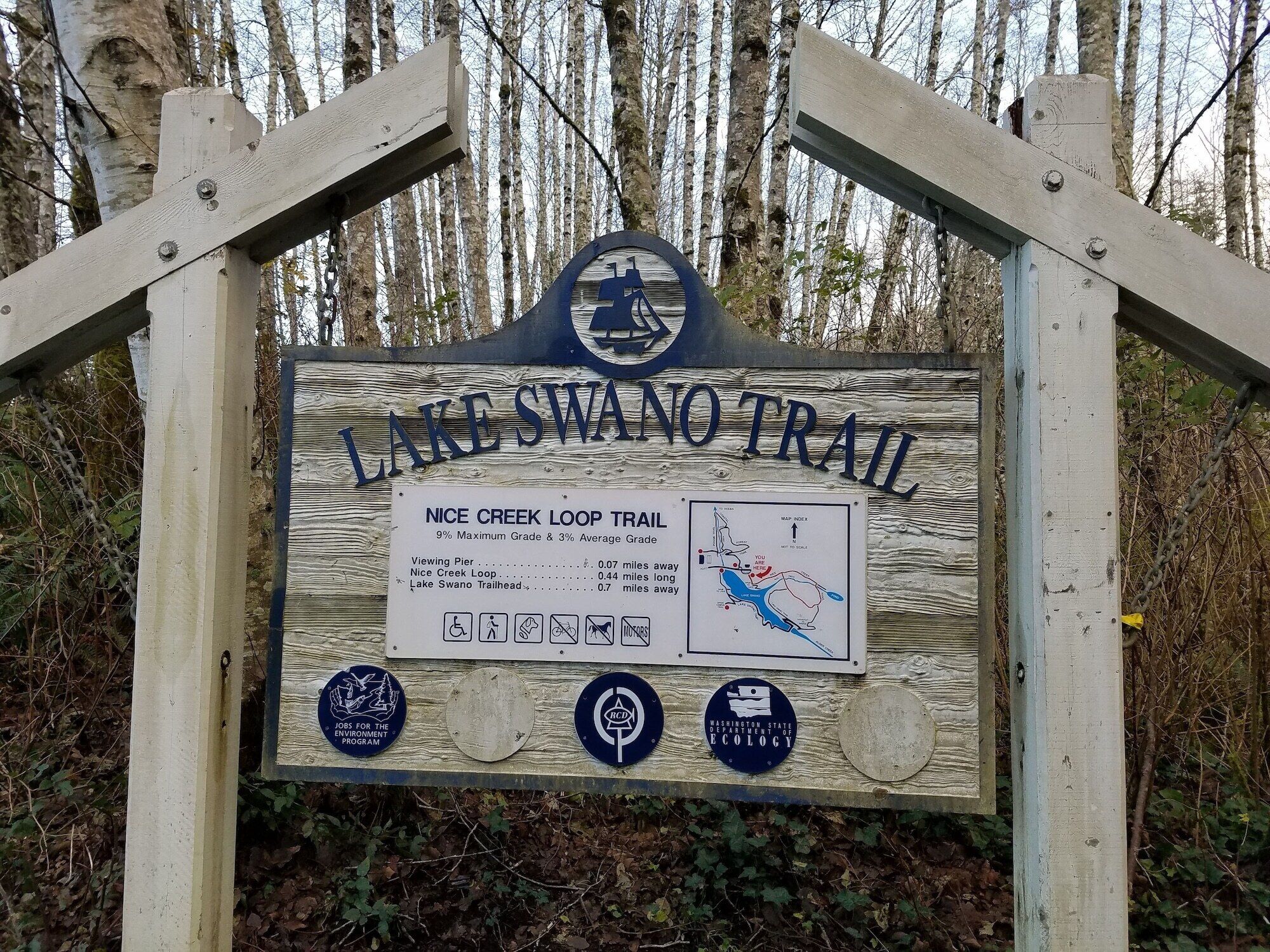 A wooden sign for the Lake Swano Trail with a map and trailhead distances.