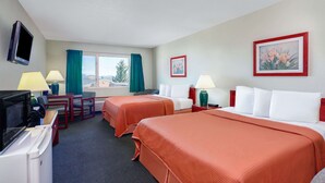 A hotel room with two beds, a desk with a TV, a lamp, and a window with curtains. - Howard Johnson Helena (Helena)