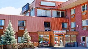 A modern hotel with a red facade, a 'Welcome' sign, and a visible car parked outside. - Howard Johnson Helena (Helena)