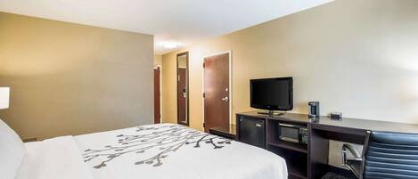 A hotel room with a bed, a desk with a computer, a television, and a microwave.