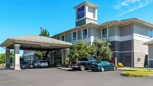 A Sleep Inn hotel with a covered parking area, a central entrance, and a prominent tower with the Sleep Inn logo. - Sleep Inn & Suites Dunmore (Scranton)