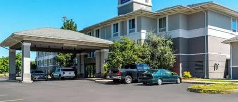 A Sleep Inn hotel with a covered parking area, a central entrance, and a prominent tower with the Sleep Inn logo.