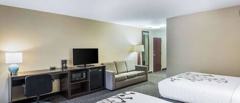A hotel room with a bed, a desk, a chair, a television, a sofa, and a lamp.