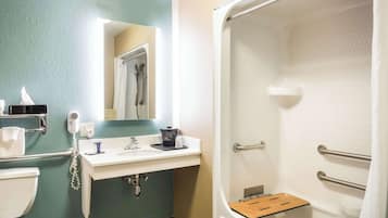 Een badkamer met een witte wastafel, een spiegel, een handdoekhouder, een douche met een houten zitje en een toilet.