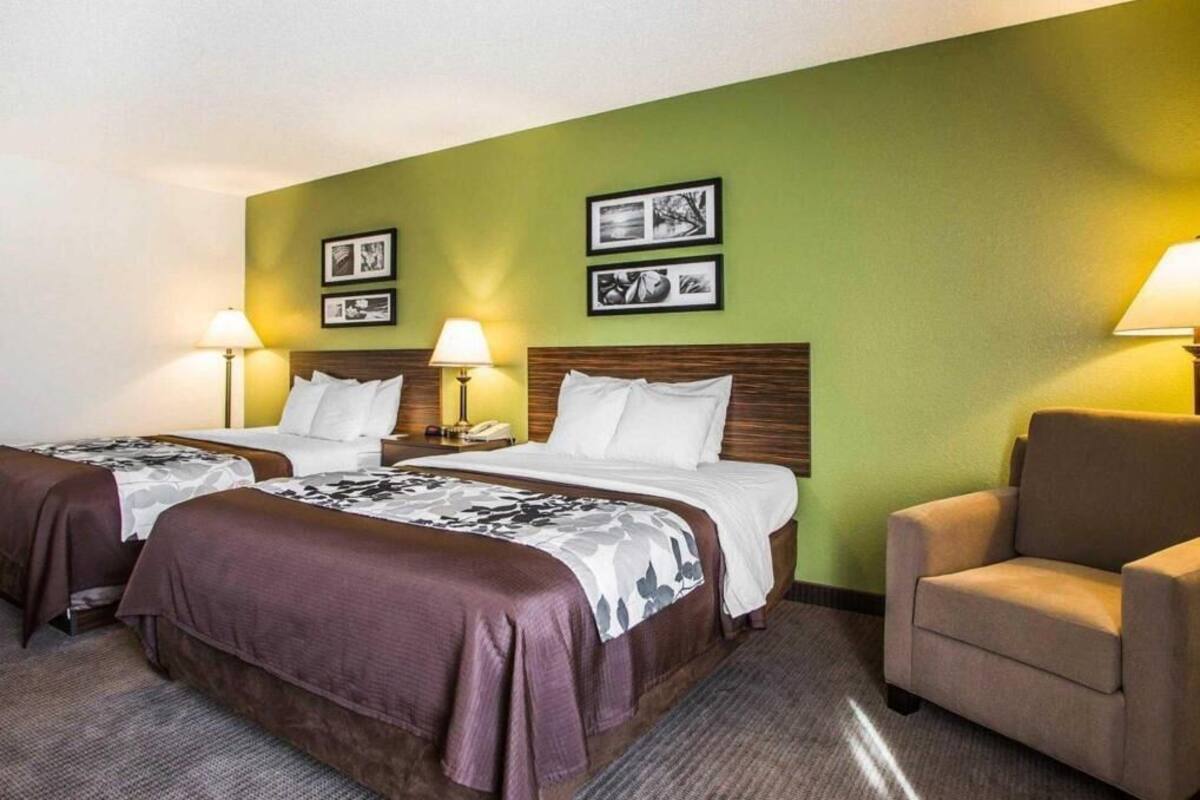 A hotel room with two beds, a sofa, and a wall with framed pictures.