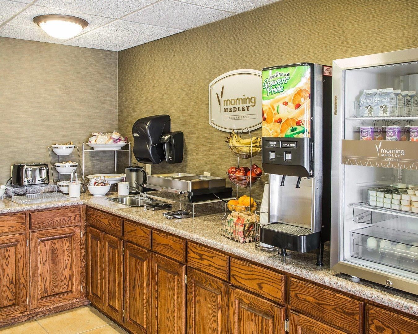 A breakfast bar with a coffee maker, juice dispenser, and refrigerated display of milk cartons.