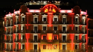 Un hotel a più piani con balconi decorati e un ingresso centrale.