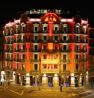 Hotel de vários andares com varandas ornamentadas e entrada central.