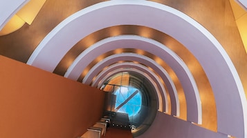 Design arquitetônico moderno com uma série de arcos e um elevador de vidro.