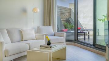 Una sala de estar moderna con un sofá, sillones, una mesa de centro y un ventanal con vistas a una terraza exterior.