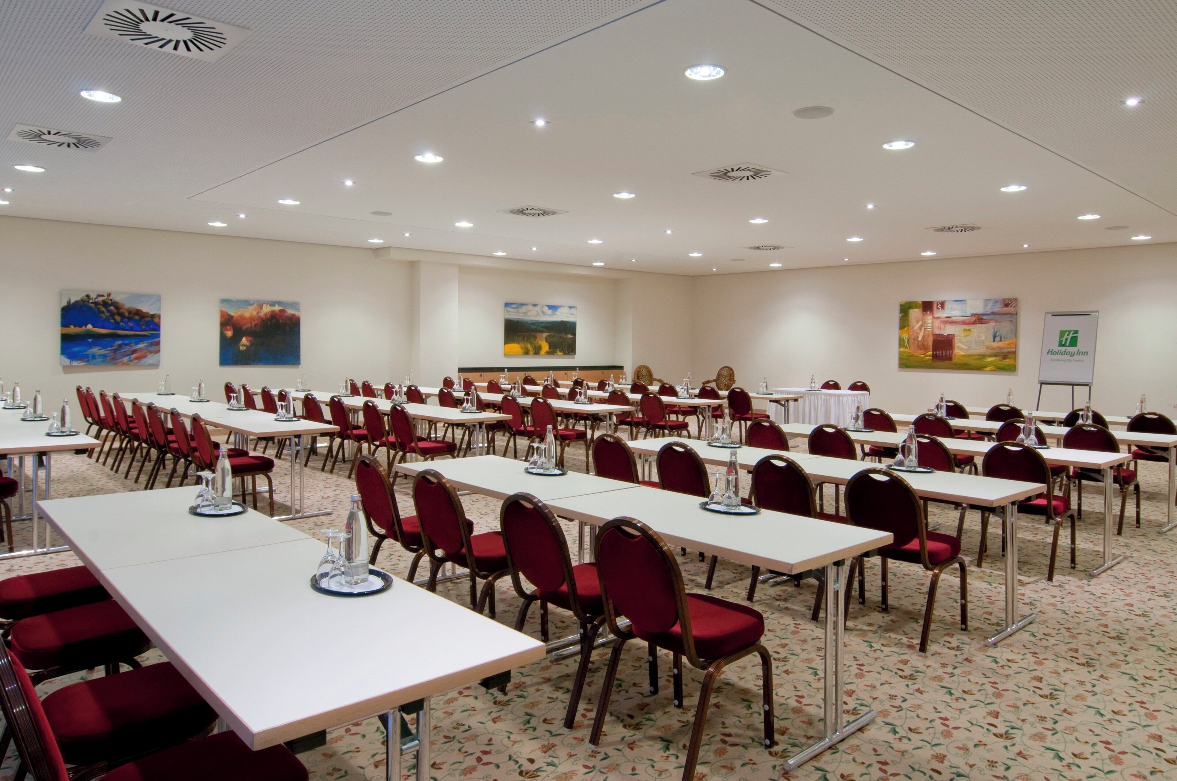 Una sala de conferències amb diverses taules i cadieres, equipada amb ampolles d'aigua i matisos.