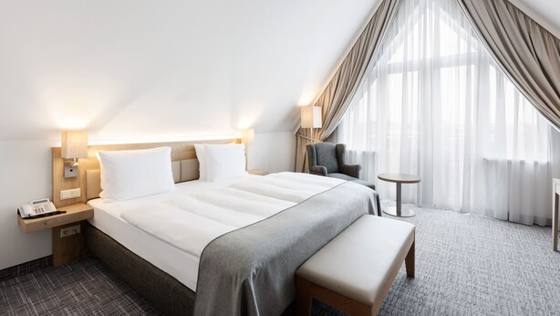 Et moderne hotelværelse med en stor seng, sengeborde, et skrivebord og en stol.