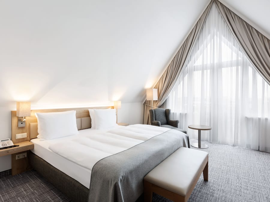 A modern hotel room with a large bed, bedside tables, a desk, and a chair.