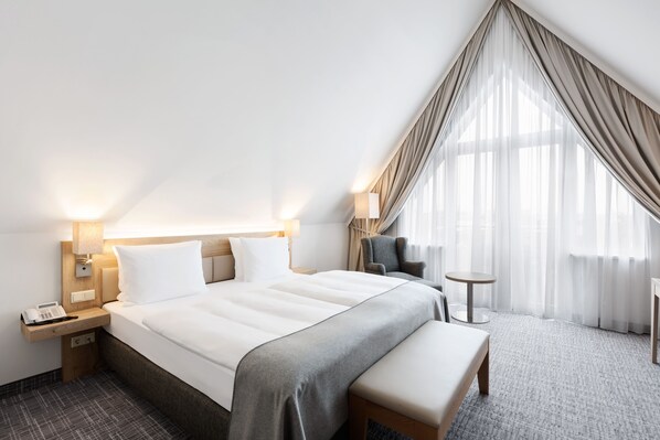 A modern hotel room with a large bed, bedside tables, a desk, and a chair. - Holiday Inn Nürnberg City Centre by IHG (Nuremberg)