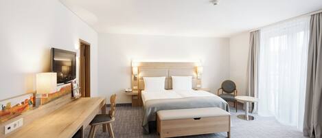 A hotel room with a bed, bedside tables, a desk with a chair, a television, and a window with curtains.