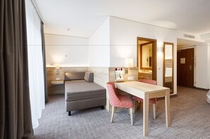 A hotel room with a bed, a desk, a chair, a mirror, and a bathroom door. - Holiday Inn Nürnberg City Centre by IHG (Nuremberg)