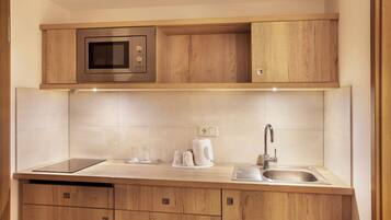 Una cocina moderna con microondas integrado, un lavamanos y armarios de madera.