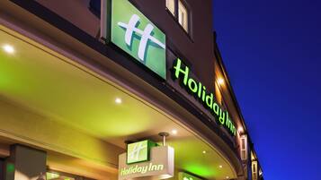 Un panneau Holiday Inn avec une flèche verte pointant vers la gauche, indiquant l’emplacement du parking.