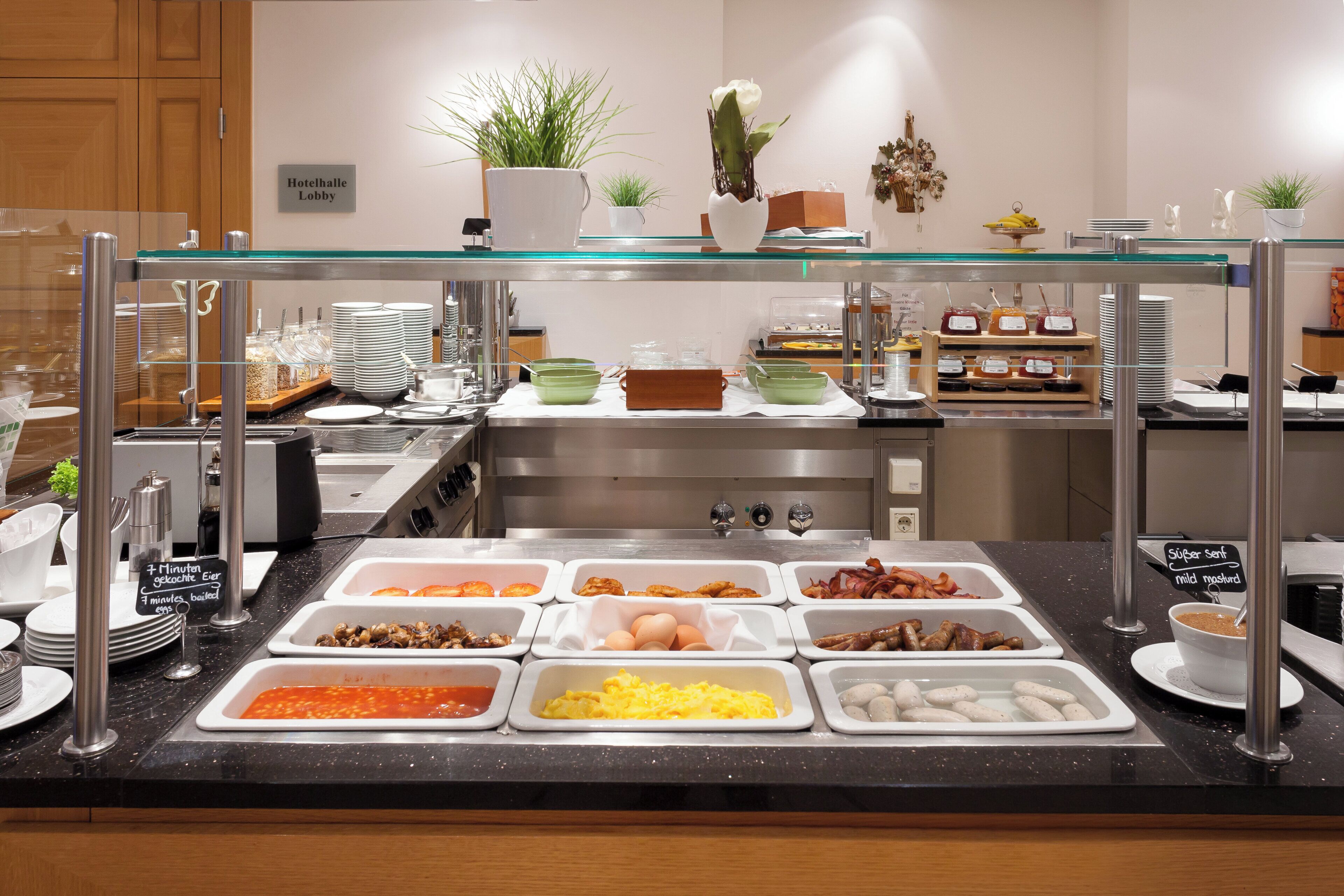 A buffet area with various food options, including eggs, sausages, and a selection of condiments.