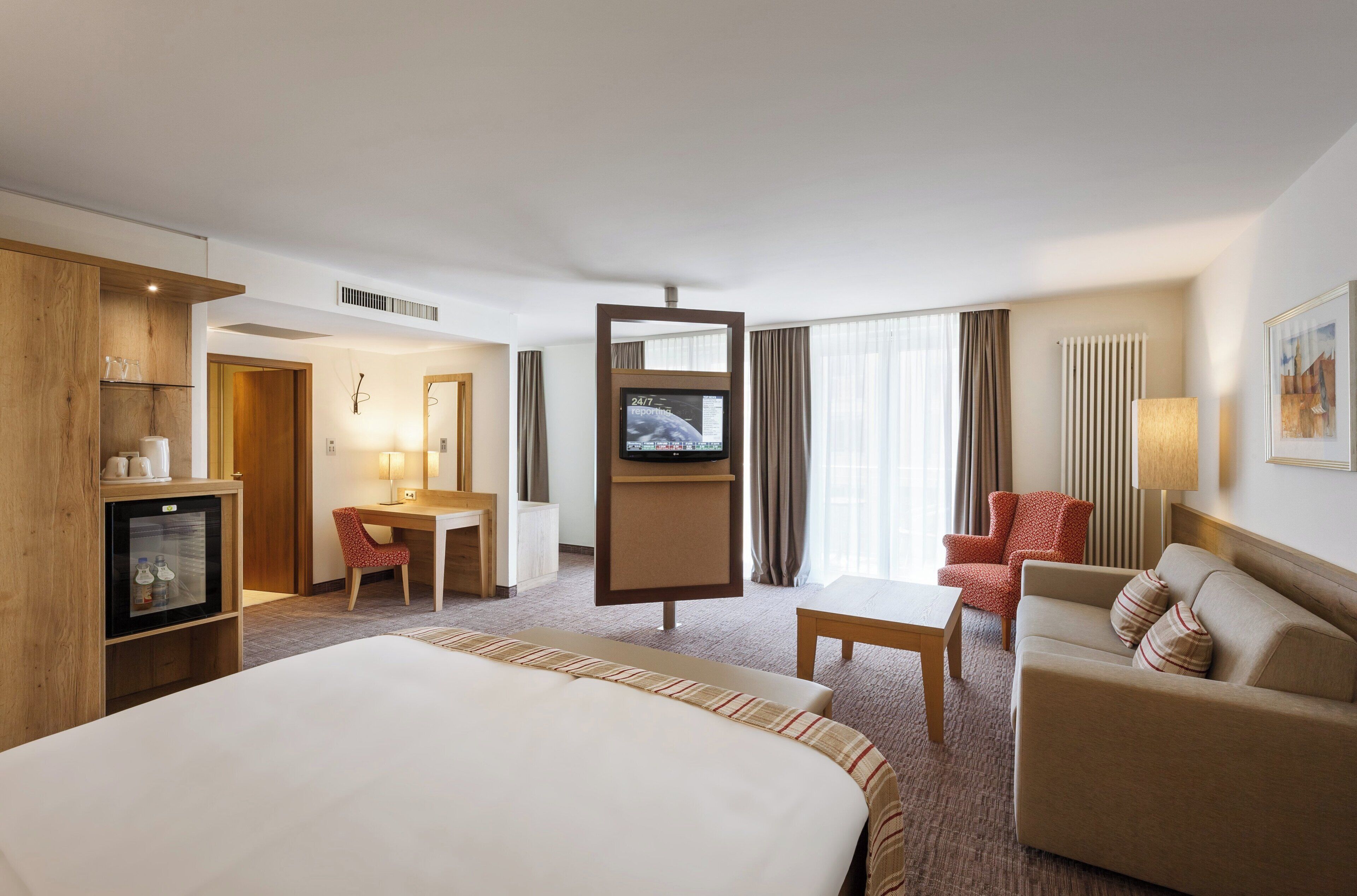 Une chambre d’hôtel avec un lit, un bureau, une télévision, un canapé et une chaise.