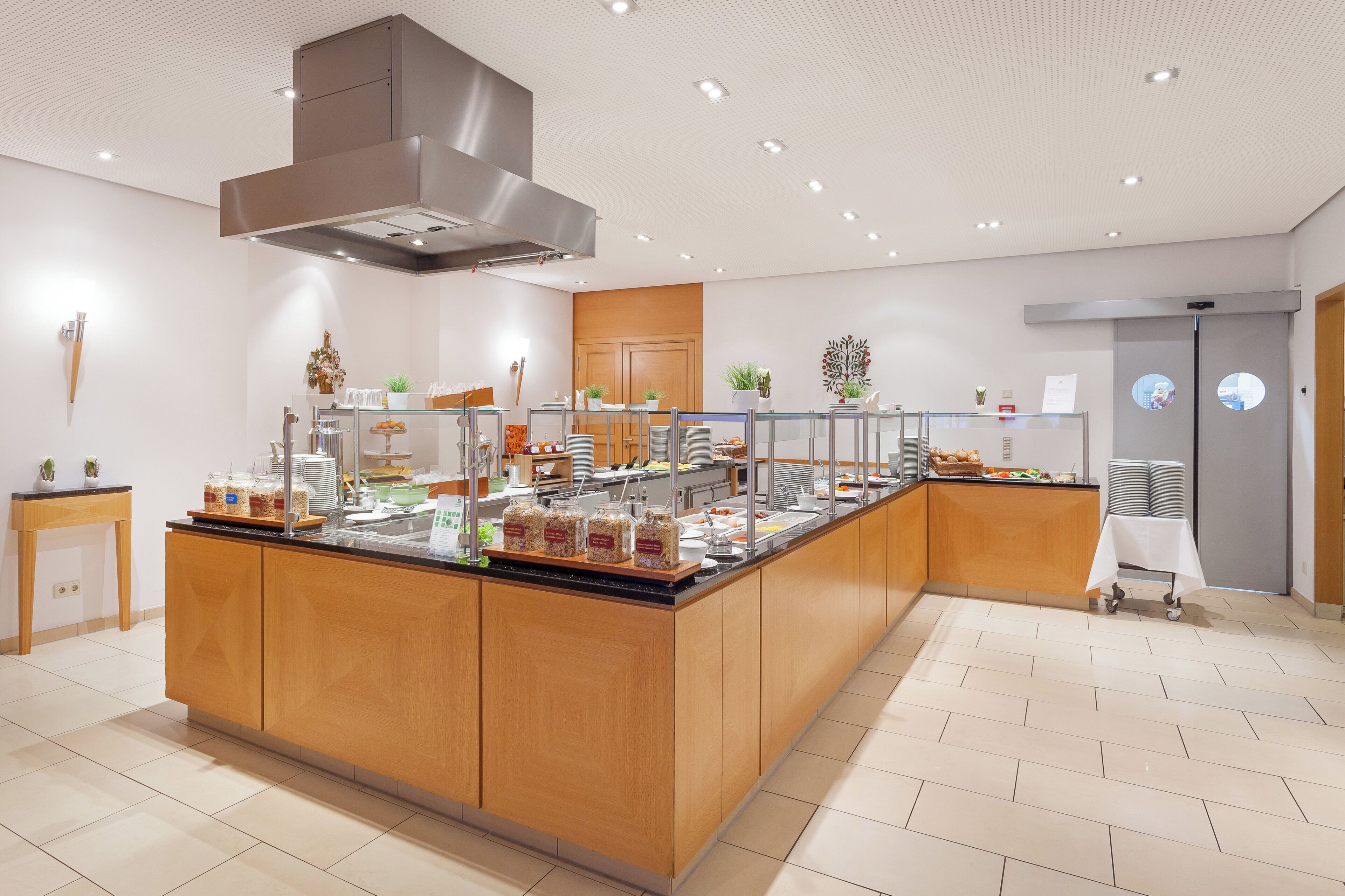 A modern breakfast bar with a variety of food options, a stainless steel range hood, and a clean, tiled floor.