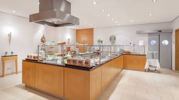 A modern breakfast bar with a variety of food options, a stainless steel range hood, and a clean, tiled floor.