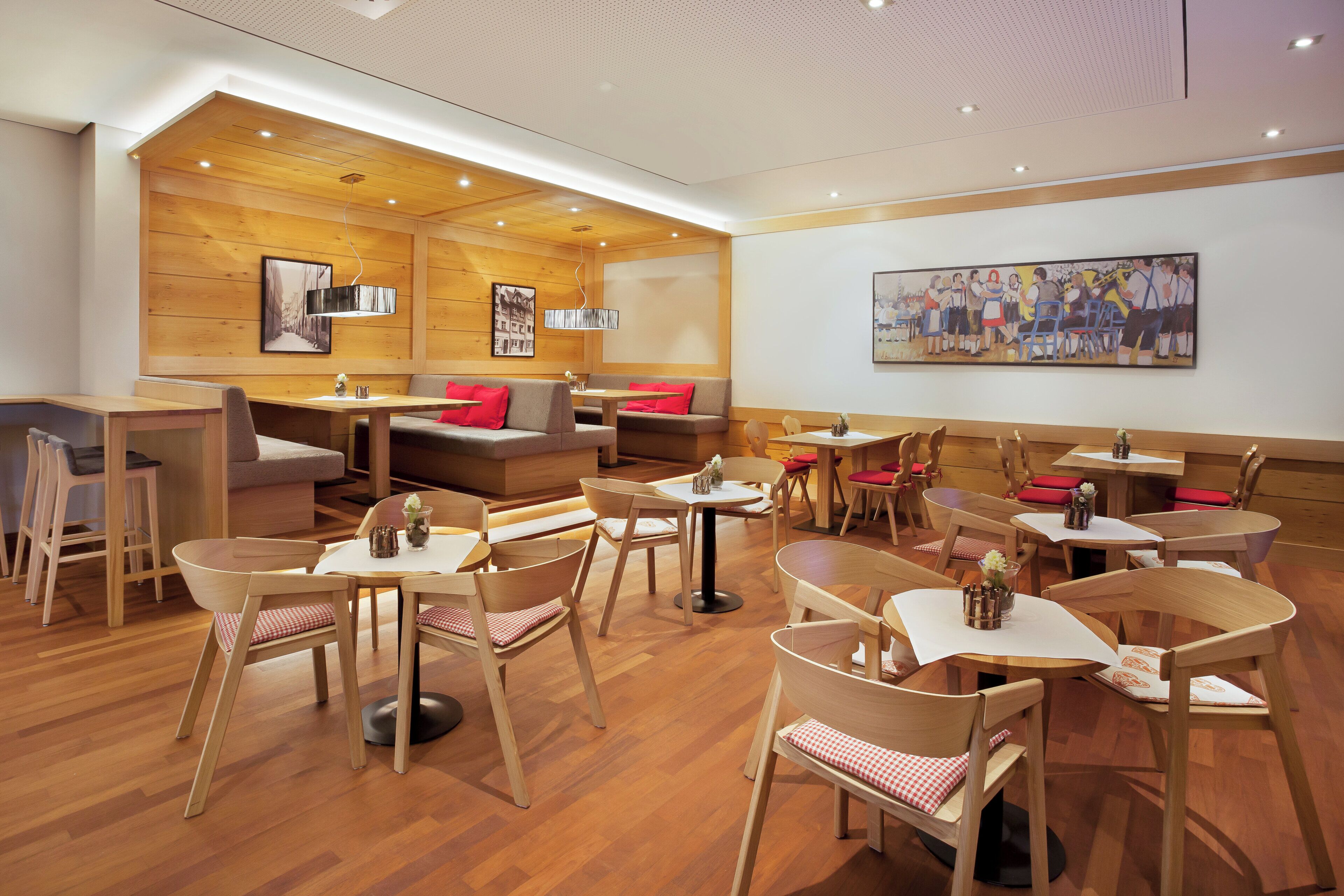 A modern interior with wooden panel walls, a variety of seating options including tables and benches, and artwork on the walls.