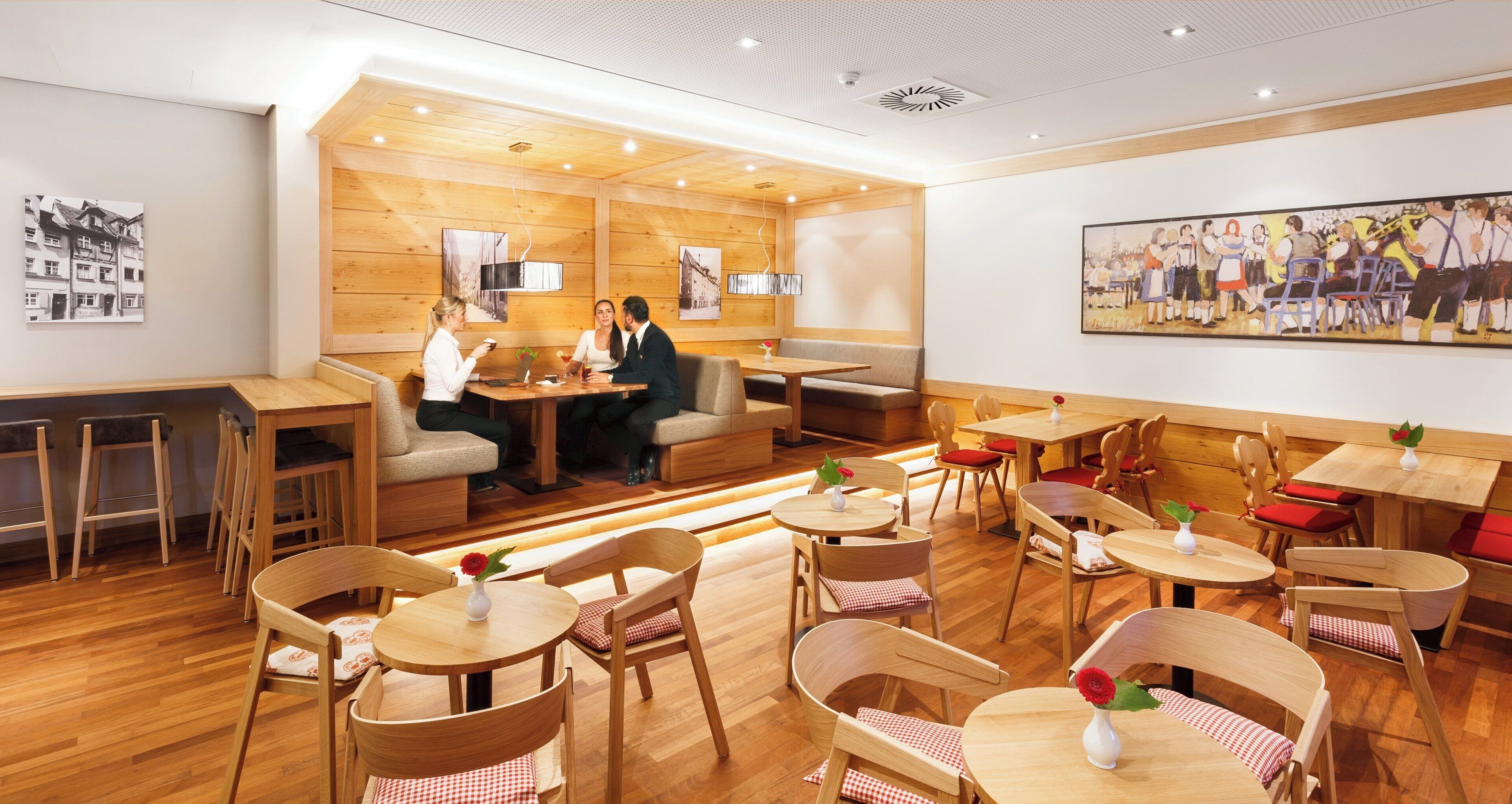 A restaurant interior with wooden panel walls, multiple seating arrangements, and artwork on the walls.