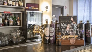 A bar area with various bottles and glasses, a refrigerator, and a poster on the wall. - Best Hotel (Riga)