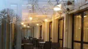 A restaurant with a glass ceiling, wooden tables, and chairs. - Best Hotel (Riga)